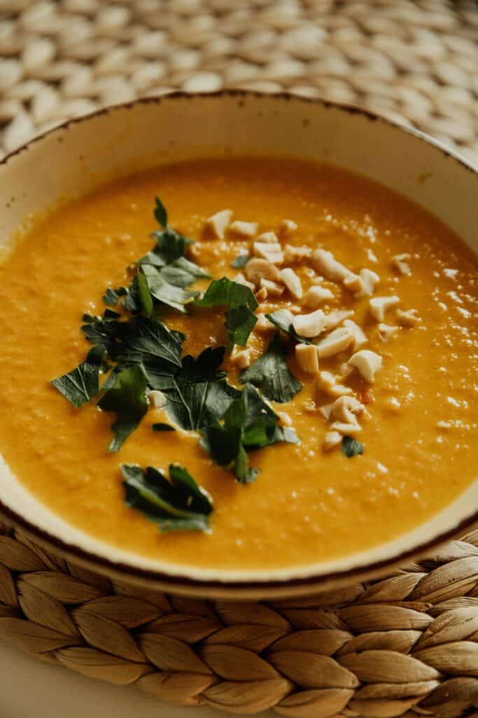 Image d'un potage aux couleurs orangées, garni de feuilles aromatiques, symbolisant les bienfaits des soupes pour la saison hivernale