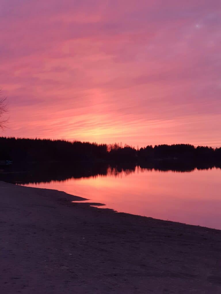 Instant magique : coucher de soleil sur un lac, entouré de forêt, depuis une plage