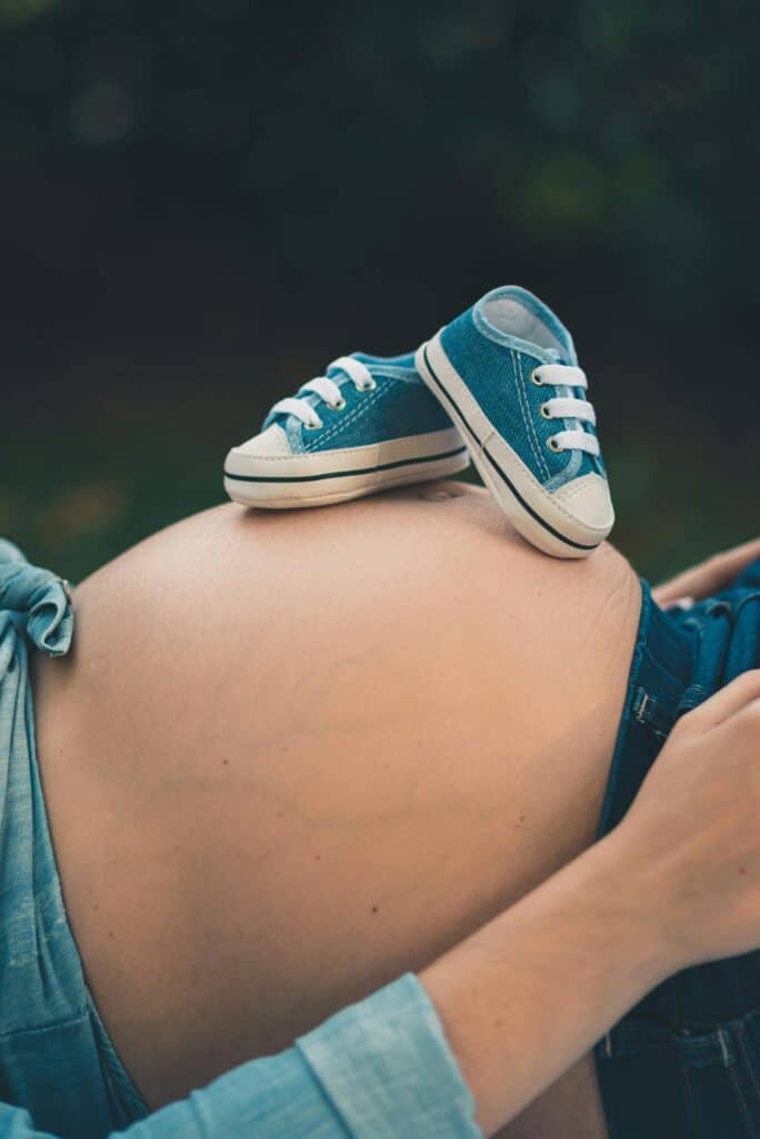 Relaxation guidée pour femmes enceintes : petites chaussures de bébé posées sur le ventre d'une future maman