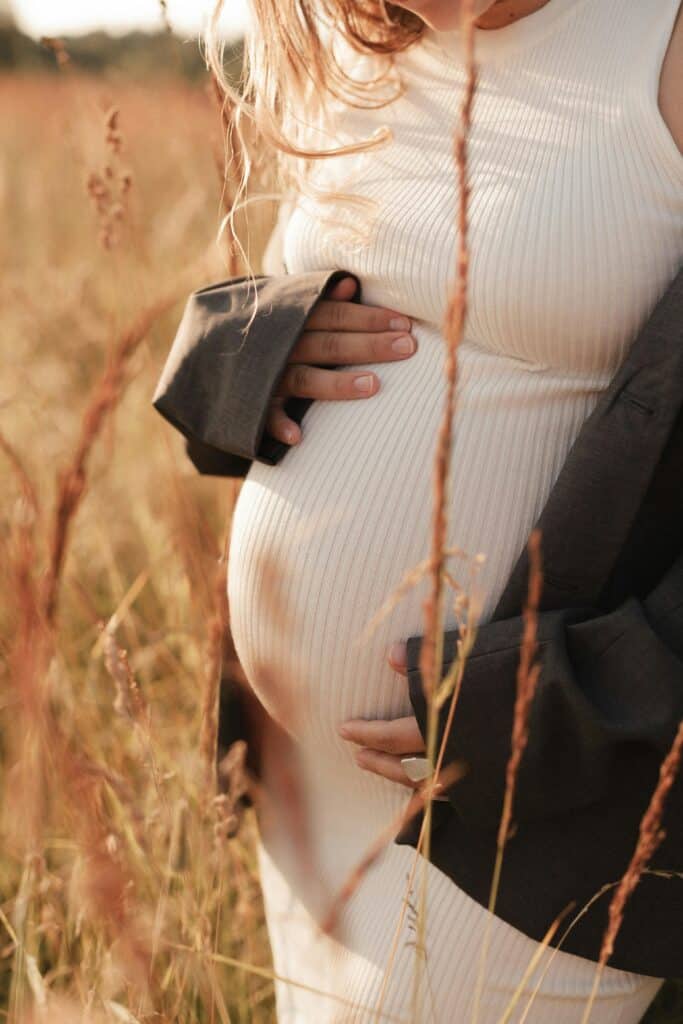 Grossesse et relaxation : future maman posant les mains sur son ventre en plein air