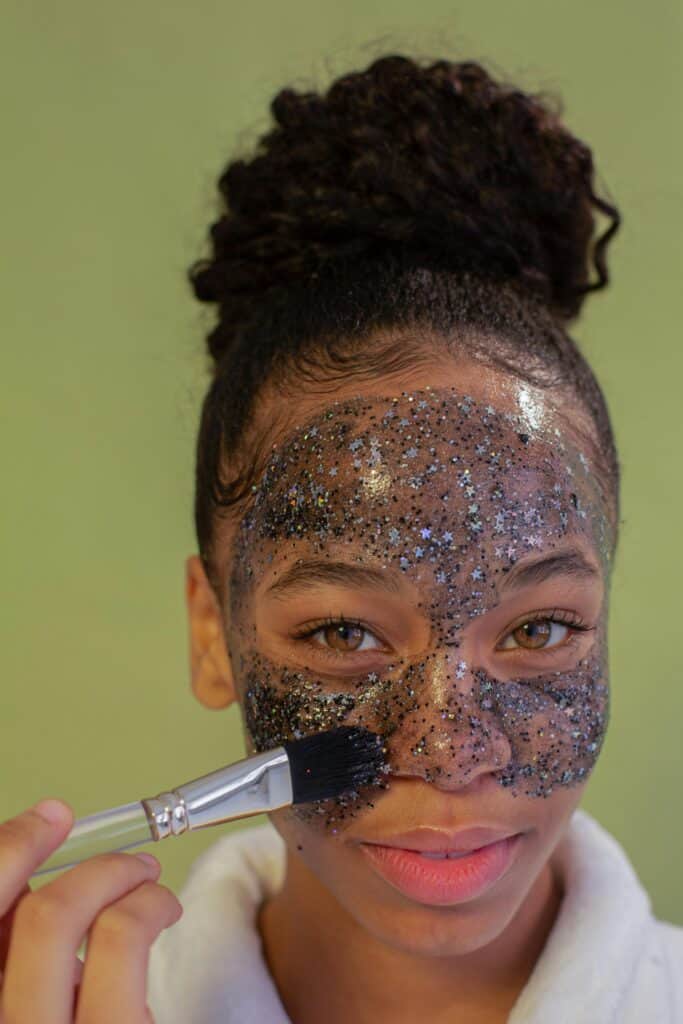 Femme utilisant un pinceau pour appliquer un masque d'argile sur son visage, illustrant une routine de soin pour la peau