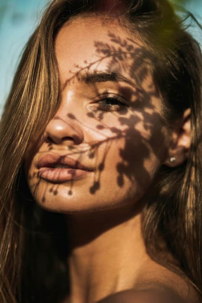 Femme avec un visage ombragé par des fleurs, représentant l'harmonie entre nature et soins de la peau