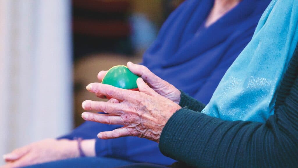 Exercice de rééducation des mains avec une balle, pratiqué par une personne âgée souffrant d’arthrite