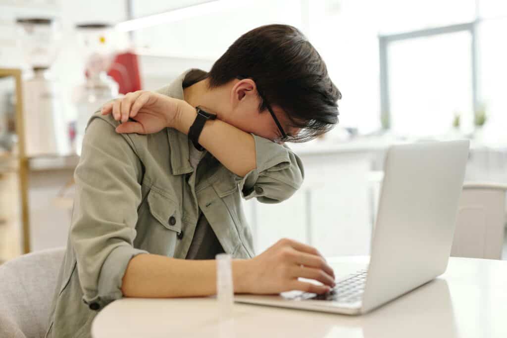 Homme enrhumé éternuant pendant son télétravail, illustrant une immunité affaiblie en hiver